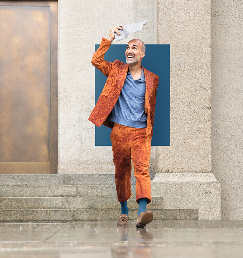 A man is walking through the city in the rain. He is wearing compression socks in the trendy colour Casual Blue