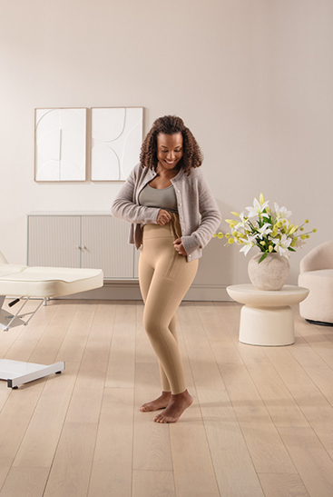 Lifestyle Juzo Comprima Leggins Eine dunkelhaarige Frau schließt gerade den Reißverschluss der Juzo Comprima Leggins