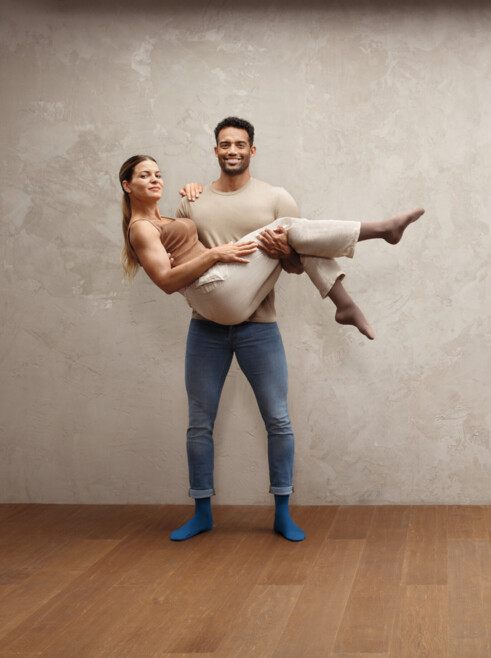 Strong man holding woman in his arms, both wearing Juzo Intenso