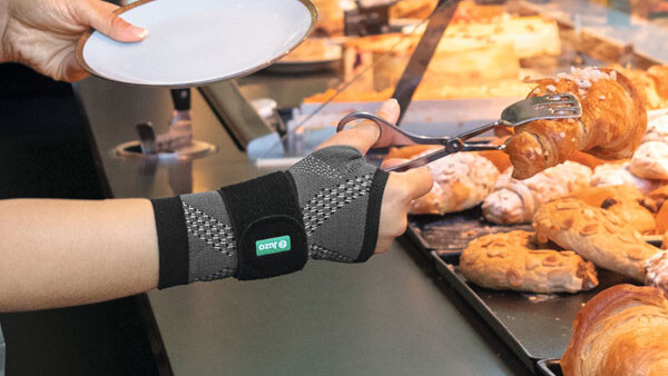 Eine Verkäuferin in der Bäckerei trägt eine Handgelenkbandage bei der Arbeit Eine Verkäuferin in der Bäckerei trägt eine Handgelenkbandage bei der Arbeit